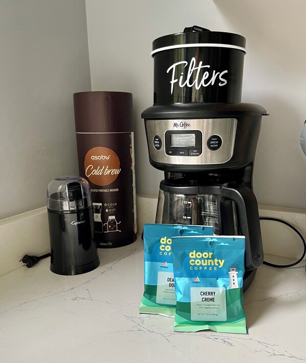 A coffee maker, a coffee pod dispenser, and two coffee pods labeled "Door County Coffee" on a countertop.