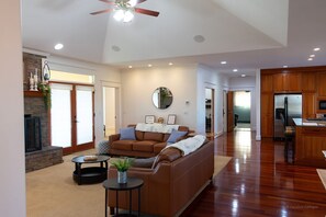 Amplia sala de estar con chimenea, un sofá y una zona de comedor con armarios de madera.