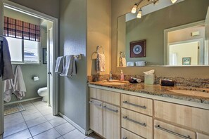 Un bagno moderno con un piano di lavoro in granito, uno specchio grande e un water.