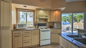 A kitchen with wooden cabinets, a microwave, a stove, and a coffee maker. -  Walk to White Sands Beach   Ocean view 2 Bedroom with pool (Kailua-Kona)