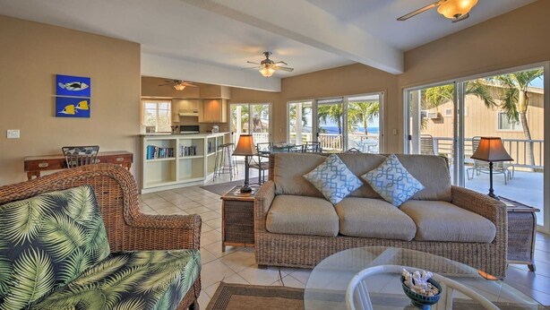A spacious living area with a sofa, chairs, and a dining table. There is a kitchen area with a bar and a view of the ocean. -  Walk to White Sands Beach   Ocean view 2 Bedroom with pool (Kailua-Kona)