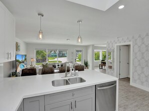 A modern kitchen with a large island, double sink, and pendant lighting. - Beachside Haven with Pool & BBQ. 6 min to Beach (Pompano Beach)
