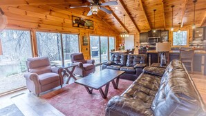 A log cabin interior with a living area, dining space, and kitchen. - Riverfront | Hot Tub, Fireplace, Kayaks & Tubes (Evart)