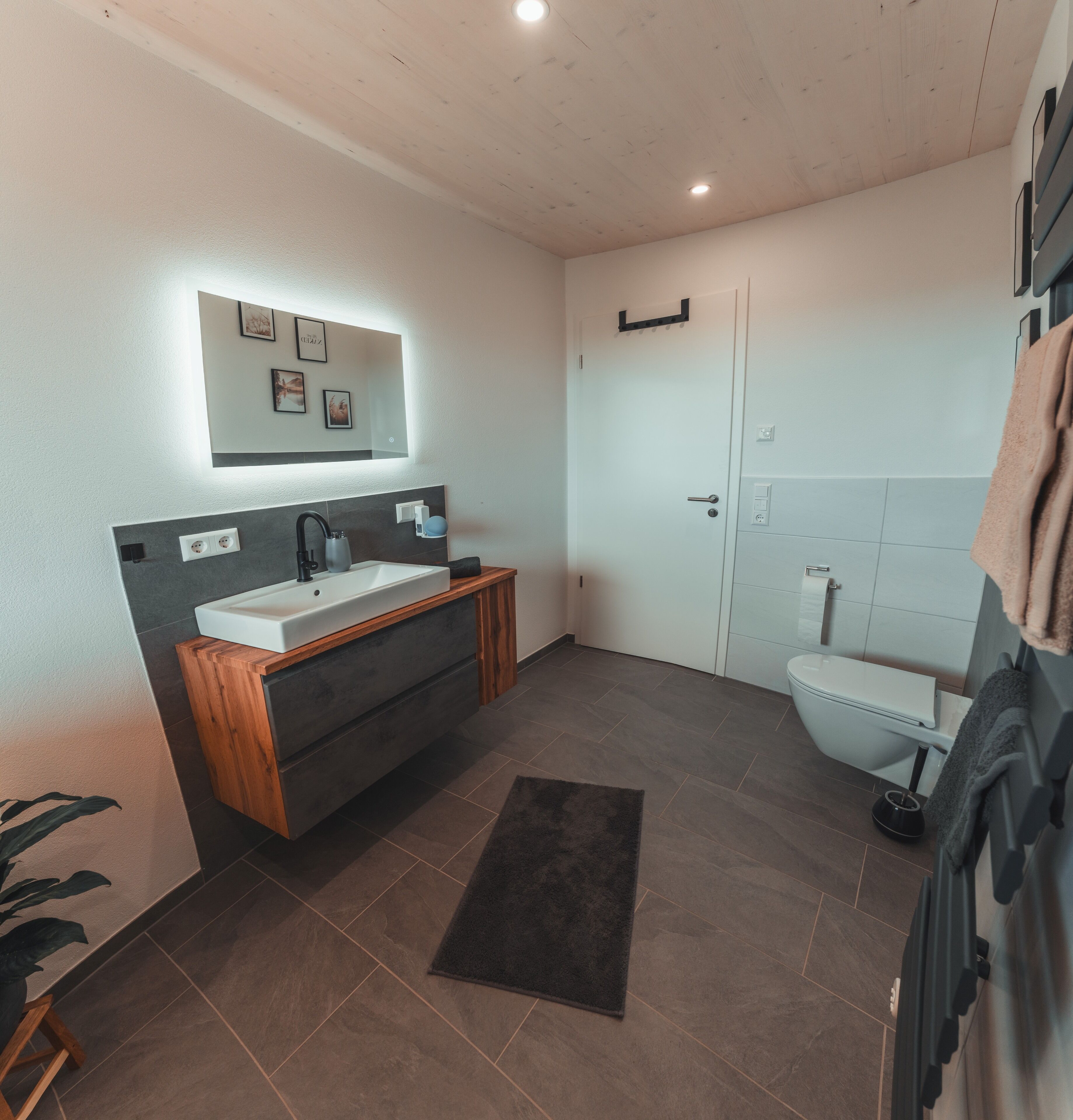 Une salle de bain moderne avec un meuble-lavabo en bois, un grand miroir et des toilettes.
