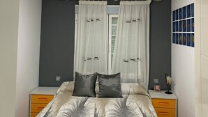Een slaapkamer met een bed, twee nachtkastjes, een lamp, en een raam met gordijnen.