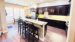 A modern kitchen with dark wood cabinets, a central island with bar stools, and pendant lighting.