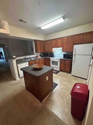 Kitchen features a central island, microwave, stove, and refrigerator.