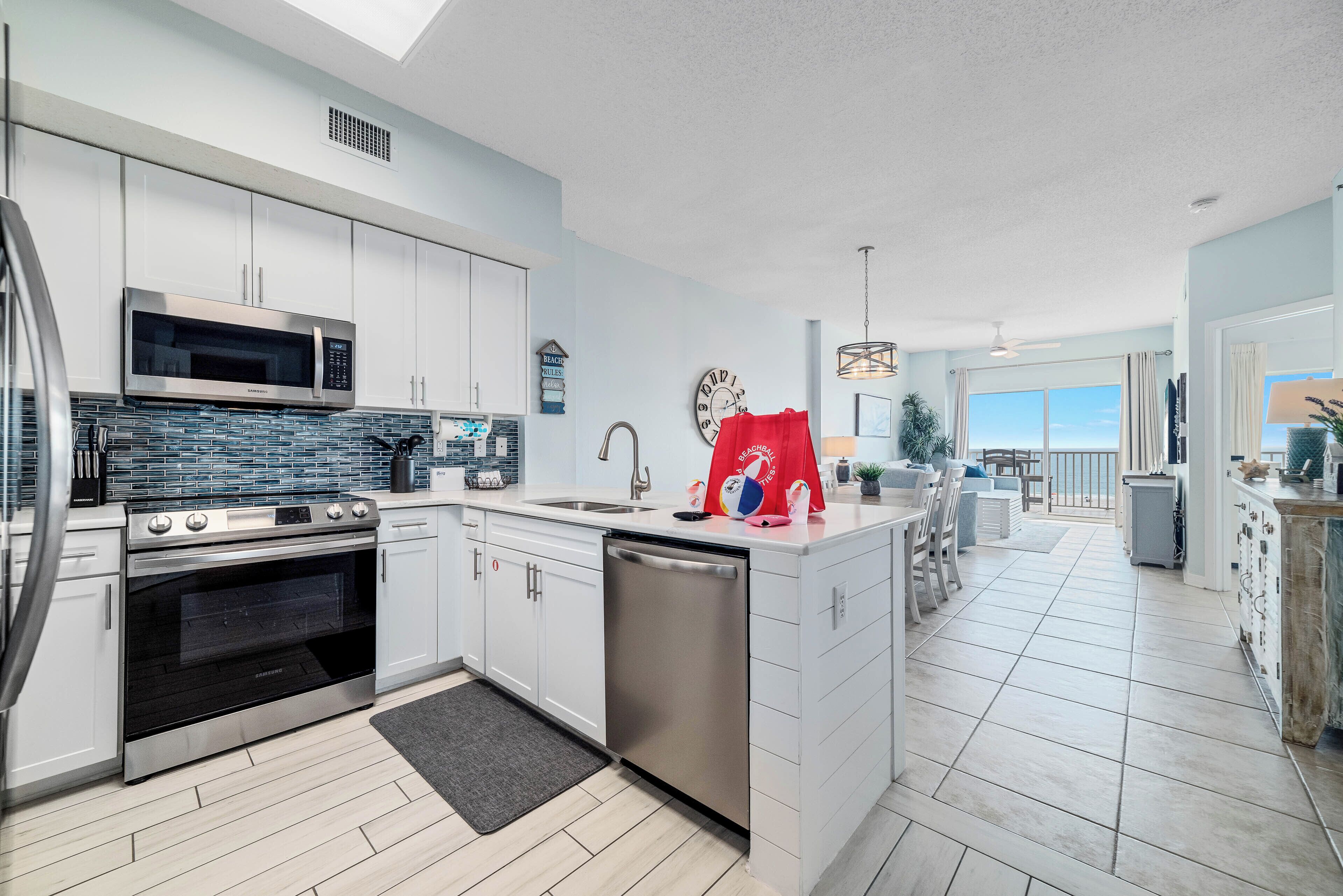A modern kitchen with white cabinets, stainless steel appliances, and a large island.