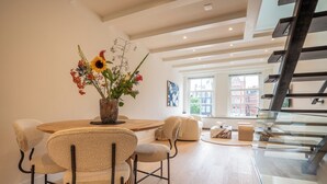 A modern dining area with a wooden table, beige upholstered chairs, and a floral centerpiece. - Elegant, sophisticated and unique canal house part of the famous canal district (Amsterdam)