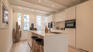 A modern kitchen with white cabinetry, a central island with stools, and a built-in oven. - Elegant, sophisticated and unique canal house part of the famous canal district (Amsterdam)