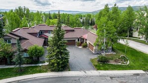 A residential area with multiple houses, a driveway, and a well-maintained lawn. - A Ducking Good Time! AC, Large Deck with Hot Tub & 2 Car Garage! (Steamboat Springs)