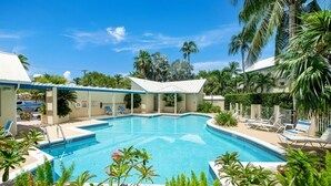Une piscine avec des chaises longues et des palmiers.
