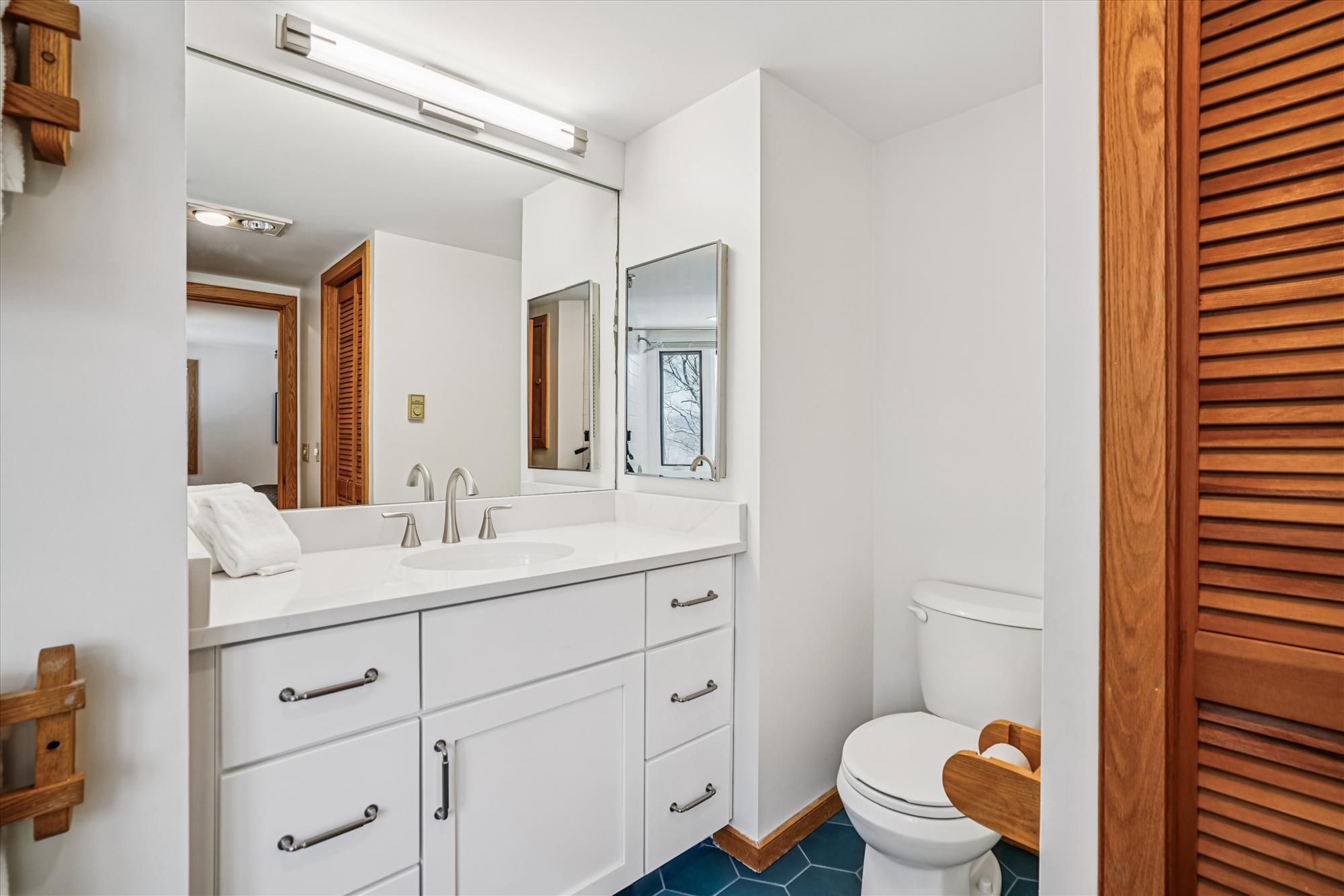 Une salle de bain moderne avec un meuble-lavabo blanc, deux vasques, un grand miroir et des toilettes.
