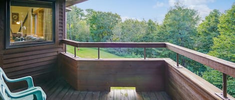 Una terraza de madera con barandilla, un banco y vistas a un paisaje boscoso.