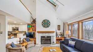 A modern living room with a fireplace, a sofa, a coffee table, and a television.