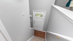 A narrow stairway with a white door at the top and a wooden floor. - Quaint 4bd Home - 3 min to Adventureland & Casino! (Altoona)