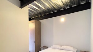 Une chambre moderne avec un grand lit, une armoire en bois et une petite table de chevet.
