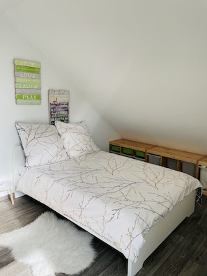 Une chambre avec un lit, un tapis blanc et moelleux, un banc en bois et des œuvres d’art murales inspirantes.