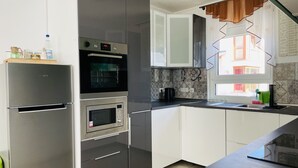 Ett modernt kök med rostfria vitvaror, en inbyggd ugn och ett fönster med gardiner.