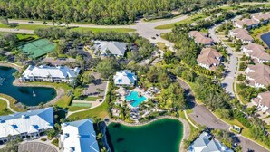 An aerial view of a residential area with houses, a swimming pool, and a tennis court. - GARDENIA at Greenlinks - 3 Bedroom Lake View Golf Villa (Naples)