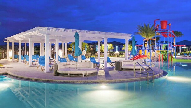 A pool area with lounge chairs, a covered seating area, and a water slide. - Windsor Peace | Pool Home Near Attractions (Kissimmee)