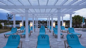 A covered outdoor seating area with rows of blue lounge chairs, each marked with a 'W'. - Windsor Peace | Pool Home Near Attractions (Kissimmee)