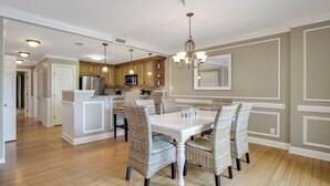A spacious kitchen with a central island, wooden cabinets, and a dining area with wicker chairs and a white table.