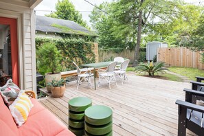 Um deck de madeira com móveis de exterior, uma área coberta para sentar e um jardim.