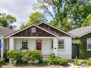 A single-story house with a red door, a small porch, and a number plaque.