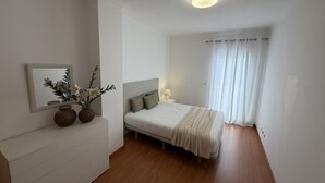 Une chambre à coucher avec un lit, une table de chevet, une lampe et un miroir au mur.