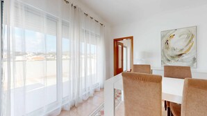 Un espace de restauration moderne avec vue sur la ville grâce à de grandes fenêtres, une table blanche et des chaises marron.