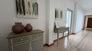 Un couloir avec un meuble, deux vases et des tableaux abstraits accrochés au mur.