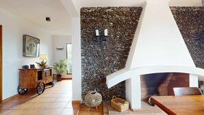 A modern interior with a stone wall, a fireplace, and a wooden dining table. - Azores Quinta DA Cruzinha (Lagoa)