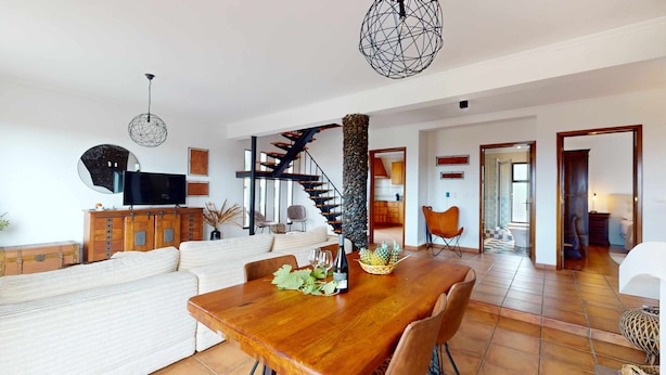 A spacious living area with a wooden dining table, a sofa set, and a staircase leading to an upper floor. - Azores Quinta DA Cruzinha (Lagoa)