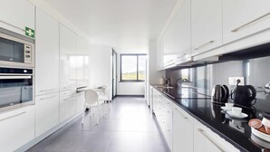 Eine moderne Küche mit weißen Schränken, einer schwarzen Arbeitsplatte und einem Fenster mit Blick ins Freie.