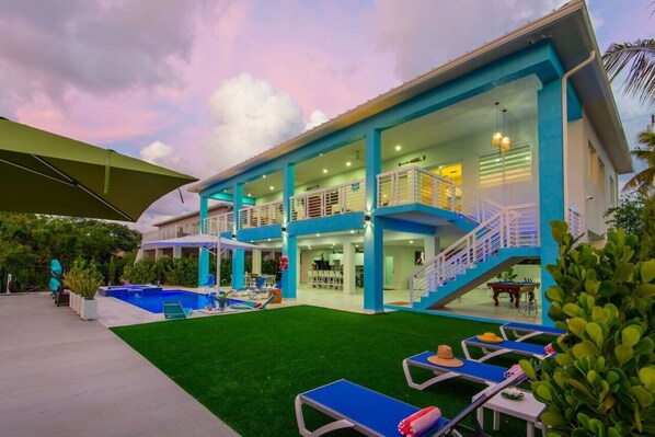 Un moderno edificio de dos pisos con piscina, asientos al aire libre y un patio cubierto.