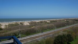 A coastal road with a beach and dunes in the background.