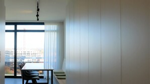 A modern, minimalist room with a large window, a dining table with chairs, and a view of a construction site.