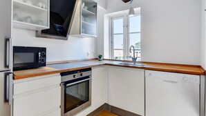 Una cocina moderna con armarios blancos, un microondas, un horno y un lavavajillas.