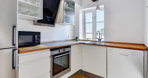 Une cuisine moderne avec des meubles blancs, un four à micro-ondes, un four traditionnel et un lave-vaisselle.