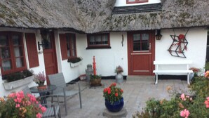 A thatched-roof building with a white exterior, red shutters, and a bench. - New Renovated Farmhouse (Slagelse)
