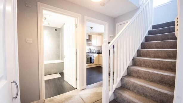 A hallway with a carpeted staircase leading to a second-floor landing. - Tranquil 2Bed/2Bath Duplex Falkirk (Falkirk)