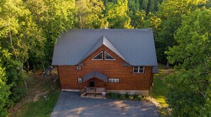 Une cabane en rondins surmontée d’un toit en métal, entourée d’une forêt dense.
