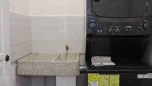 Uma cozinha compacta com pia embutida e micro-ondas preto.