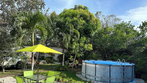 A backyard with a round swimming pool, a table with chairs, and a yellow umbrella. - Villas Winara With Private Pool and Close to Amazing Waterfalls (Curubandé)