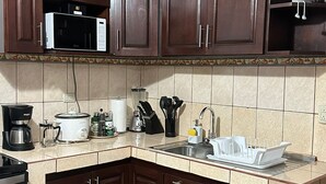 A kitchen with dark wooden cabinets, a microwave, a coffee maker, and a sink. - Villas Winara With Private Pool and Close to Amazing Waterfalls (Curubandé)