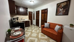 A compact living space with a kitchenette, a dining area with a table and chairs, a sofa with decorative pillows, and a refrigerator. - Villas Winara With Private Pool and Close to Amazing Waterfalls (Curubandé)