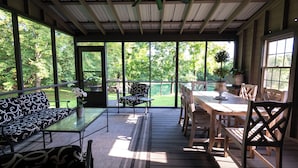 A covered outdoor area with a wooden table, chairs, and a sofa.