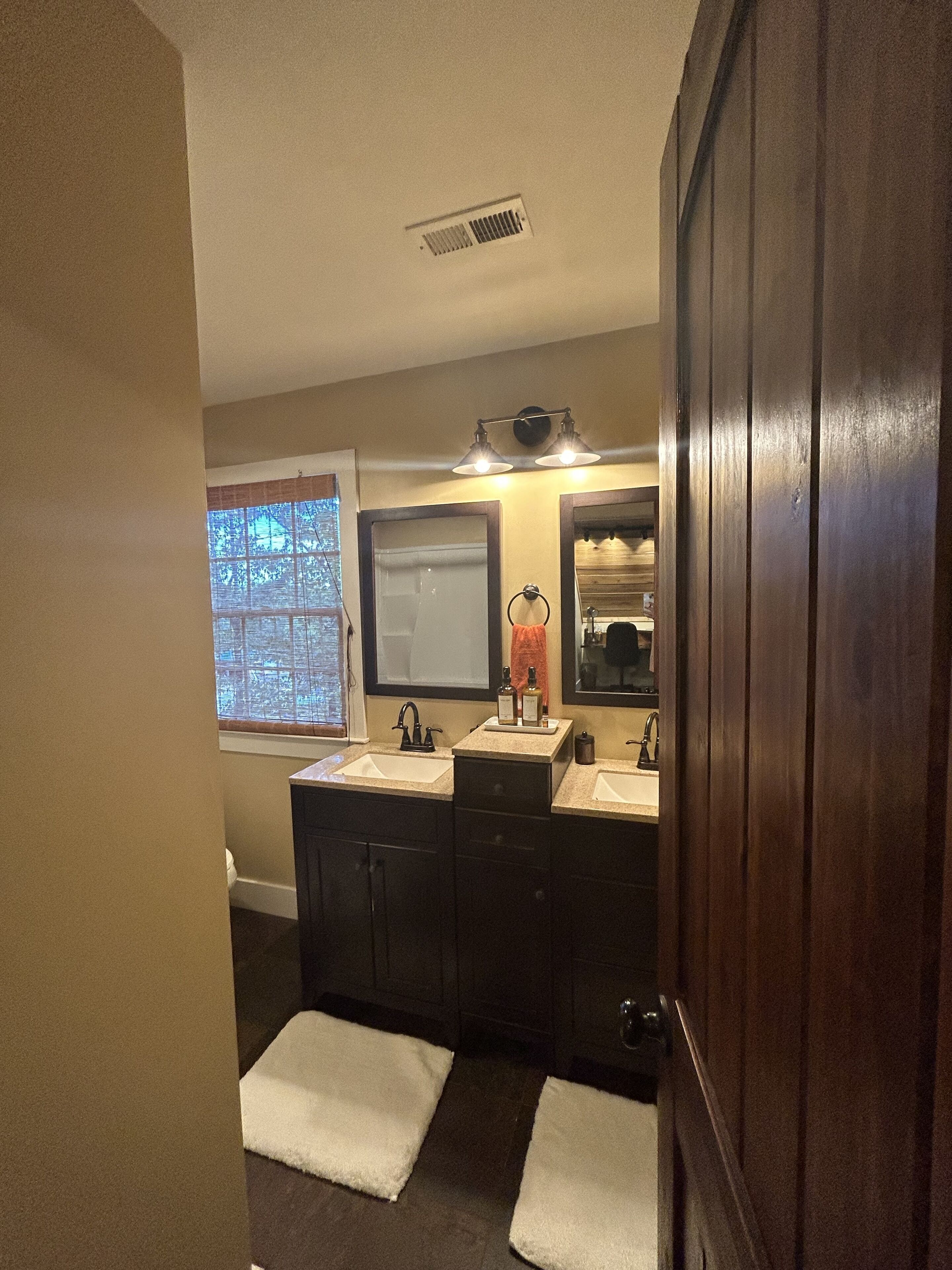 Une salle de bain avec deux lavabos, une fenêtre et un miroir.