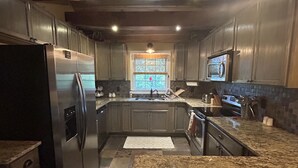 Una cocina moderna con encimeras de granito, electrodomésticos de acero inoxidable y un amplio ventanal con vidrieras.